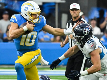 Nov 10, 2024; Inglewood, California, USA; Los Angeles Chargers quarterback Justin Herbert (10) stiff arms Tennessee Titans linebacker Jack Gibbens (50) during the second quarter at SoFi Stadium. Mandatory Credit: Robert Hanashiro-Imagn Images