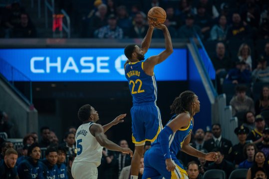 Dec 6, 2024; San Francisco, California, USA; Golden State Warriors forward Andrew Wiggins (22) makes a three point basket against Minnesota Timberwolves guard Anthony Edwards (5) during the first quarter at Chase Center. Mandatory Credit: Neville E. Guard-Imagn Images