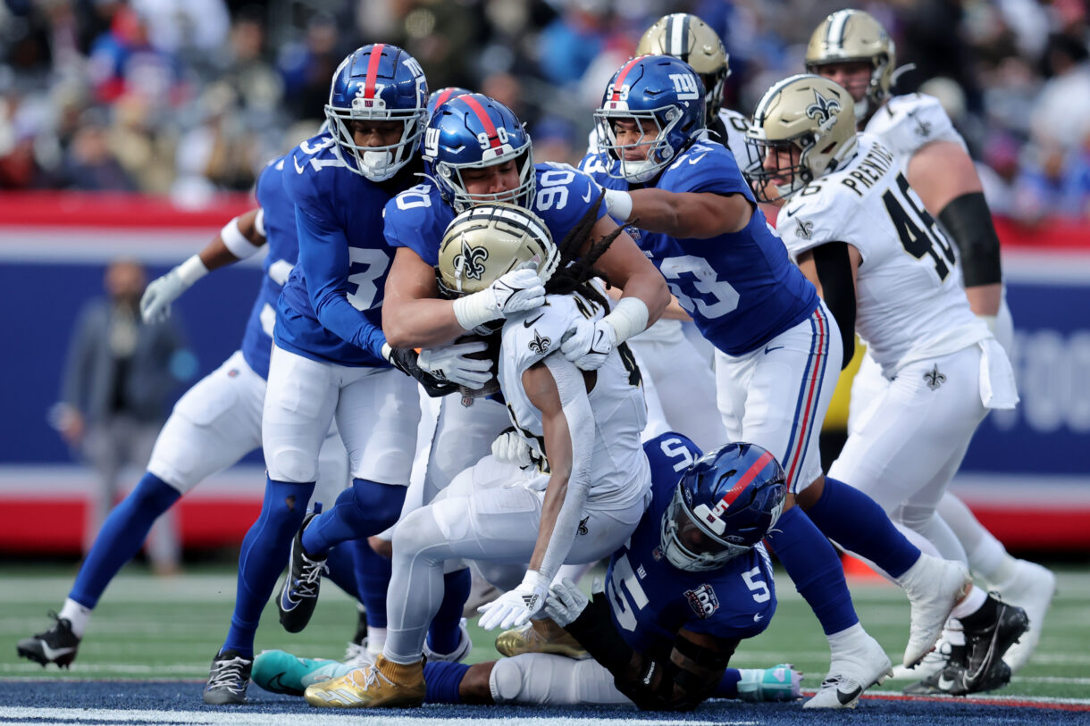 Dec 8, 2024; East Rutherford, New Jersey, USA; New Orleans Saints running back Alvin Kamara (41) is tackled by New York Giants cornerback Tre Hawkins III (37) and defensive end Elijah Garcia (90) and linebacker Darius Muasau (53) and linebacker Kayvon Thibodeaux (5) during the first quarter at MetLife Stadium. Mandatory Credit: Brad Penner-Imagn Images