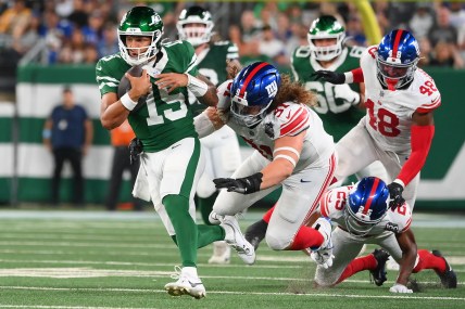 Aug 24, 2024; East Rutherford, New Jersey, USA; New York Jets quarterback Adrain Martinez (15) runs with the ball past New York Giants defensive tackle Casey Rogers (91) during the first half at MetLife Stadium. Mandatory Credit: Rich Barnes-Imagn Images