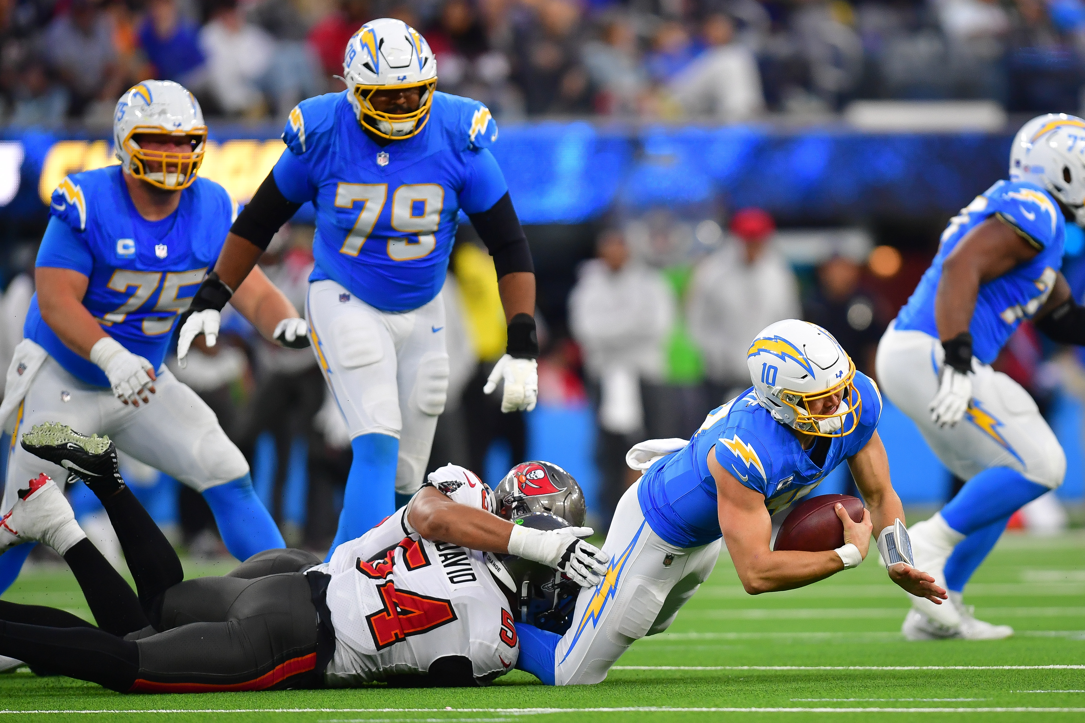 Dec 15, 2024; Inglewood, California, USA; Los Angeles Chargers quarterback Justin Herbert (10) is brought down by Tampa Bay Buccaneers linebacker Lavonte David (54) and defensive end Logan Hall (90) during the second half at SoFi Stadium. Mandatory Credit: Gary A. Vasquez-Imagn Images