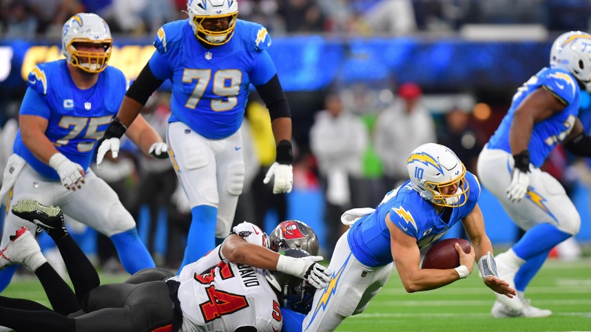 Dec 15, 2024; Inglewood, California, USA; Los Angeles Chargers quarterback Justin Herbert (10) is brought down by Tampa Bay Buccaneers linebacker Lavonte David (54) and defensive end Logan Hall (90) during the second half at SoFi Stadium. Mandatory Credit: Gary A. Vasquez-Imagn Images