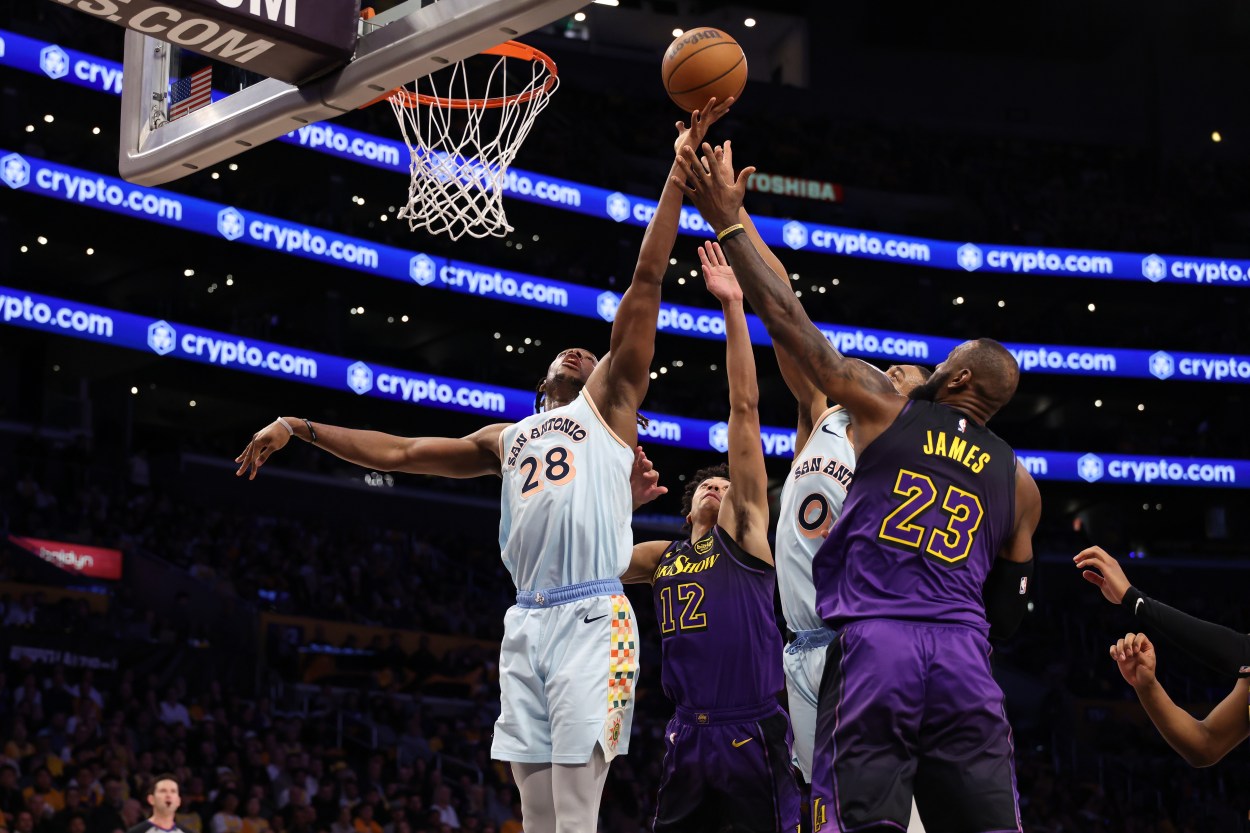 Jan 13, 2025; Los Angeles, California, USA;  San Antonio Spurs center Charles Bassey (28) rebounds a ball against Los Angeles Lakers guard Max Christie (12) and forward LeBron James (23) during the second half at Crypto.com Arena. Mandatory Credit: Kiyoshi Mio-Imagn Images