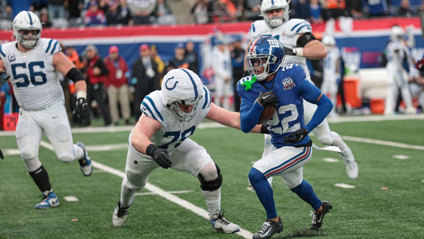 Dec 29, 2024; East Rutherford, New Jersey, USA; New York Giants cornerback Dru Phillips (22) returns an interception as Indianapolis Colts offensive tackle Bernhard Raimann (79) tackles during the second half at MetLife Stadium. Mandatory Credit: Vincent Carchietta-Imagn Images